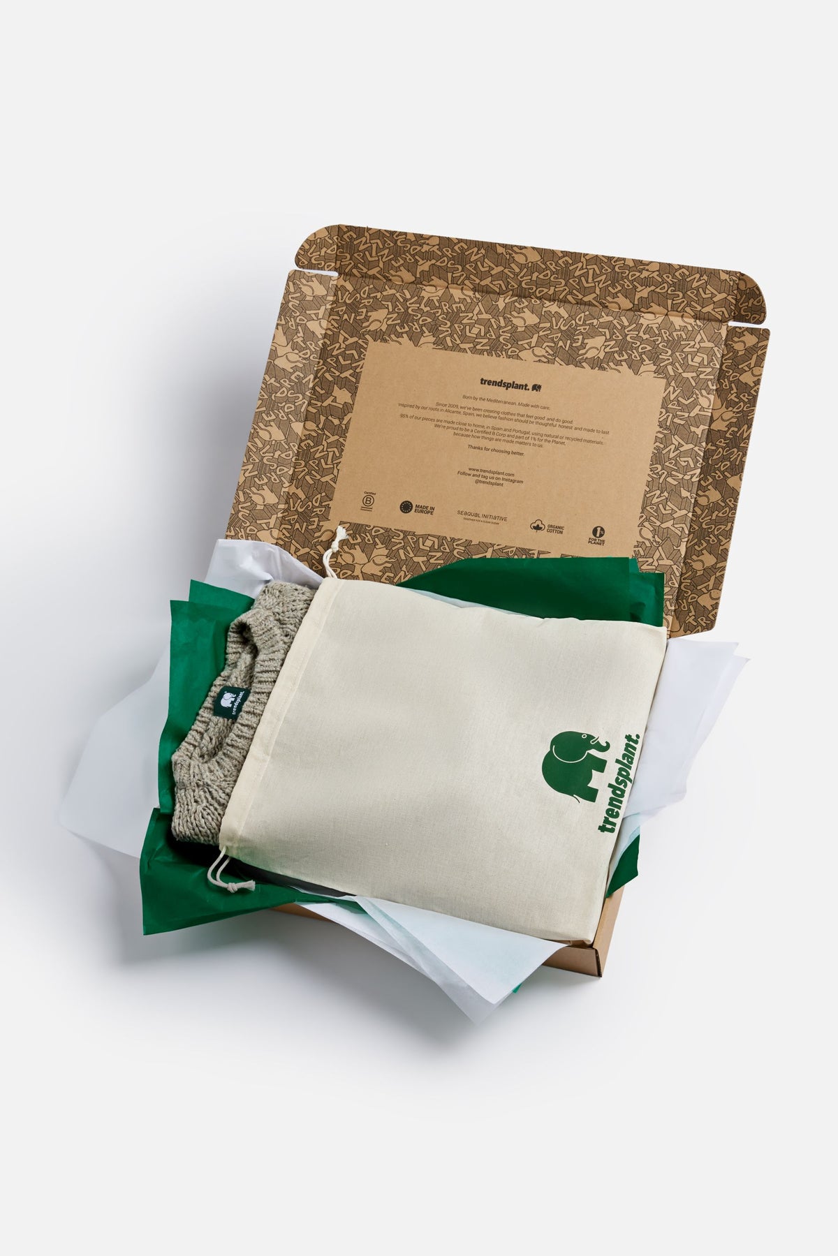 Geschenkbeutel aus Baumwolle, präsentiert mit einem kuscheligen Strickpullover und grünem Seidenpapier in einer umweltfreundlichen Verpackungsbox. | TP_IMAGE_TYPE=SILHOUETTE_FRONT