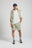 Persona che indossa gli Essential Sunwashed Sweatshorts in Seagrass, abbinati a una camicia bianca e sneakers casual, in piedi con le mani in tasca | TP_IMAGE_TYPE=MODEL_FRONT