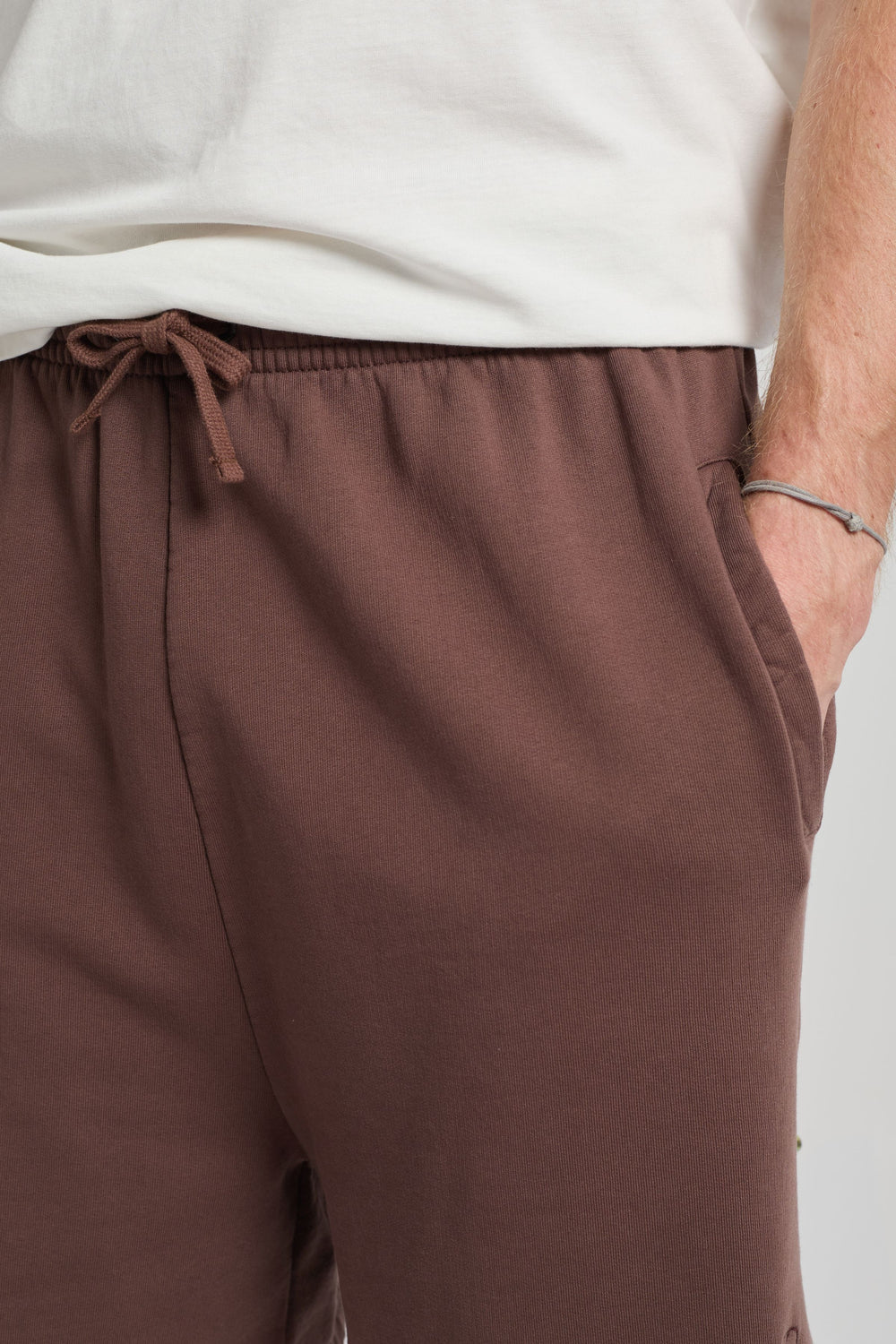 Persona che indossa Essentials Sweatshorts in Shaved Chocolate, con elastico in vita e tasche laterali in evidenza | TP_IMAGE_TYPE=DETAIL