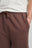 Persona che indossa Essentials Sweatshorts in Shaved Chocolate, con elastico in vita e tasche laterali in evidenza | TP_IMAGE_TYPE=DETAIL