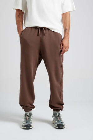 Persona che indossa Essential Sweatpants in Shaved Chocolate, con una vestibilità rilassata e coulisse in vita | TP_IMAGE_TYPE=MODEL_FRONT