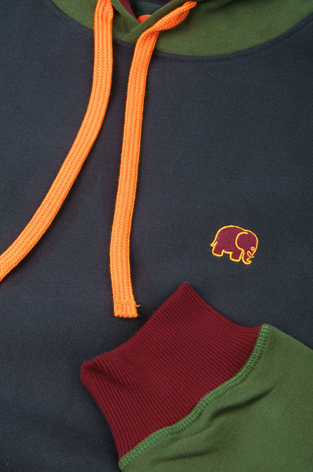 Dettaglio ravvicinato della Organic Color Block Hoodie in Trendsplant Blue, con coulisse arancione vivace, polsino bordeaux e un simpatico ricamo con elefantino. | TP_IMAGE_TYPE=DETAIL