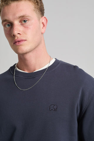 Persona che indossa una Essential Sweatshirt in Parisian Blue, con un logo elefante ricamato, abbinata a una collana a catena argentata. | TP_IMAGE_TYPE=MODEL_FRONT