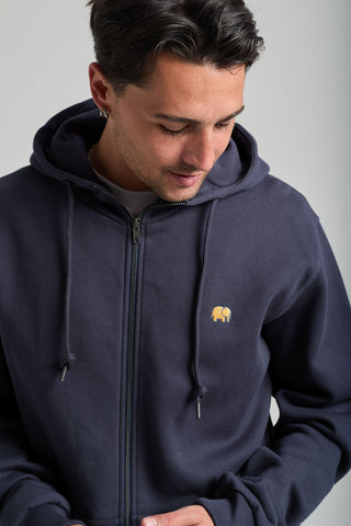 Personne portant un sweat à capuche zippé Organic Essential Zip Hoodie Trendsplant Blue avec un discret logo éléphant, vue de face | TP_IMAGE_TYPE=MODEL_FRONT