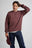 Personne portant le Essential Sweatshirt en Puce Purple, dans un style décontracté et tenant une casquette. | TP_IMAGE_TYPE=MODEL_FRONT