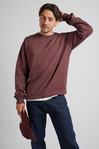 Personne portant le Essential Sweatshirt en Puce Purple, dans un style décontracté et tenant une casquette. | TP_IMAGE_TYPE=MODEL_FRONT