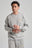 Persona che indossa Organic Essential Sweatshirt in Heather Grey, abbinata a una collana e ad anelli, rivolta verso l'obiettivo su uno sfondo neutro. | TP_IMAGE_TYPE=MODEL_FRONT