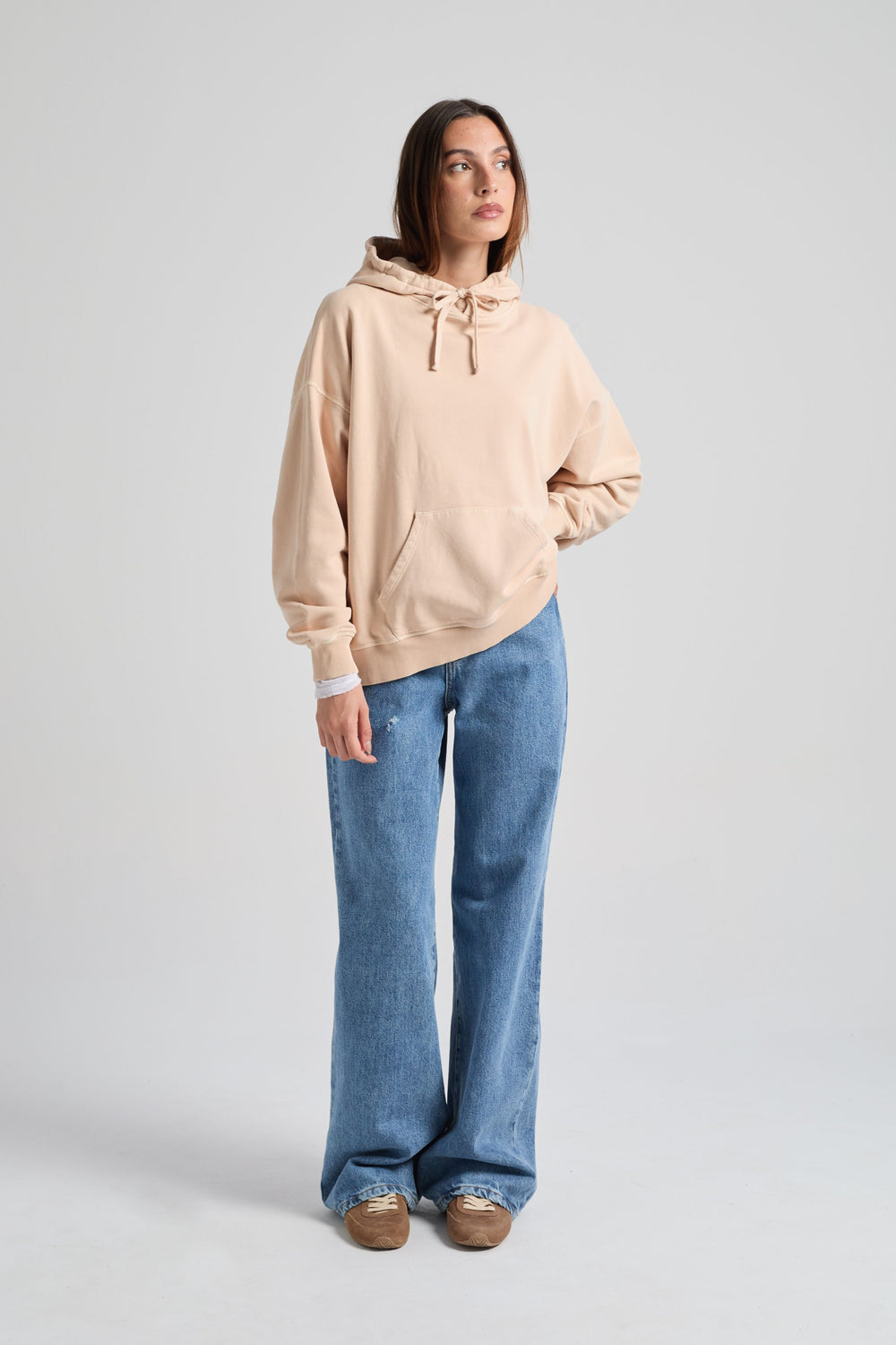 Persona che indossa una felpa beige e jeans blu su uno sfondo grigio chiaro. TP_IMAGE_TYPE=MODEL_FRONT