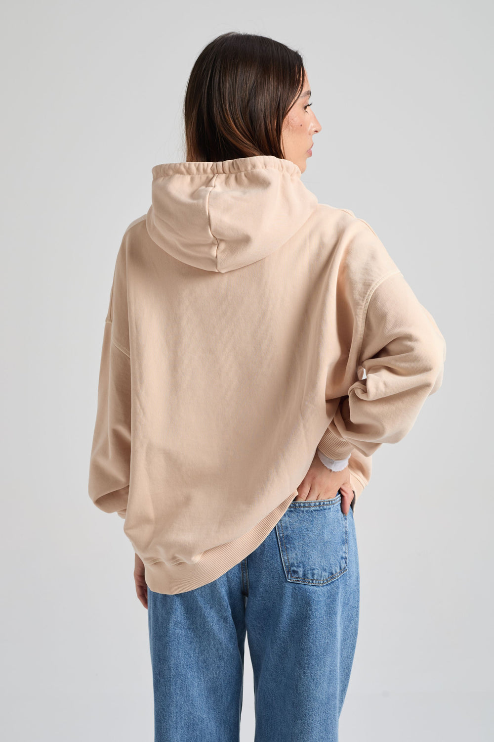 Persona che indossa una felpa beige e jeans blu su sfondo grigio chiaro. TP_IMAGE_TYPE=MODEL_BACK
