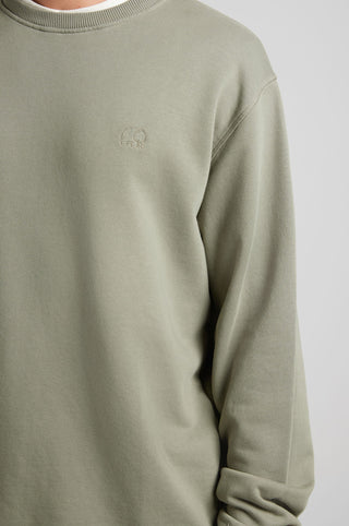 Personne portant l'Essential Sweatshirt en Agave Green, arborant un discret logo éléphant sur la poitrine | TP_IMAGE_TYPE=MODEL_FRONT