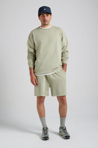 Personne portant le Essential Sunwashed Sweatshirt en coloris Seagrass, associé à un short et à des chaussures, debout dans un cadre neutre | TP_IMAGE_TYPE=MODEL_FRONT
