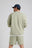 Personne portant un Essential Sunwashed Sweatshirt en Seagrass, vue de dos, assorti à un short coordonné et une casquette. | TP_IMAGE_TYPE=MODEL_BACK