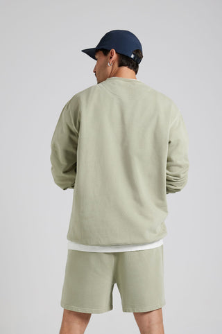 Personne portant un Essential Sunwashed Sweatshirt en Seagrass, vue de dos, assorti à un short coordonné et une casquette. | TP_IMAGE_TYPE=MODEL_BACK