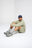 Personne portant le sweat-shirt Essential Sunwashed Sweatshirt en coloris Seagrass, assise avec une expression pensive, associée à un short et à des chaussures de sport. | TP_IMAGE_TYPE=MODEL_FRONT