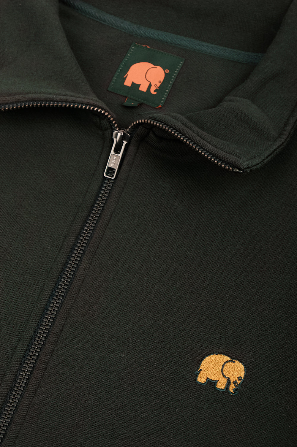Détail en gros plan de l'Organic Essential Zip Sweatshirt en Scarab Green, montrant la fermeture éclair et le logo éléphant brodé. | TP_IMAGE_TYPE=DETAIL