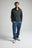 Personne portant un Organic Essential Zip Sweatshirt en Scarab Green, associé à un jean décontracté et des baskets, se tenant avec assurance sur un fond neutre. | TP_IMAGE_TYPE=MODEL_FRONT