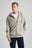 Persona che indossa la Essential Sunwashed Zip Hoodie in Natural Gray, abbinata a una t-shirt bianca e a jeans scuri, in posa in uno studio fotografico. | TP_IMAGE_TYPE=MODEL_FRONT
