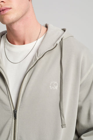 Persona che indossa la Essential Sunwashed Zip Hoodie in Natural Gray, con logo ricamato e vestibilità rilassata | TP_IMAGE_TYPE=MODEL_FRONT