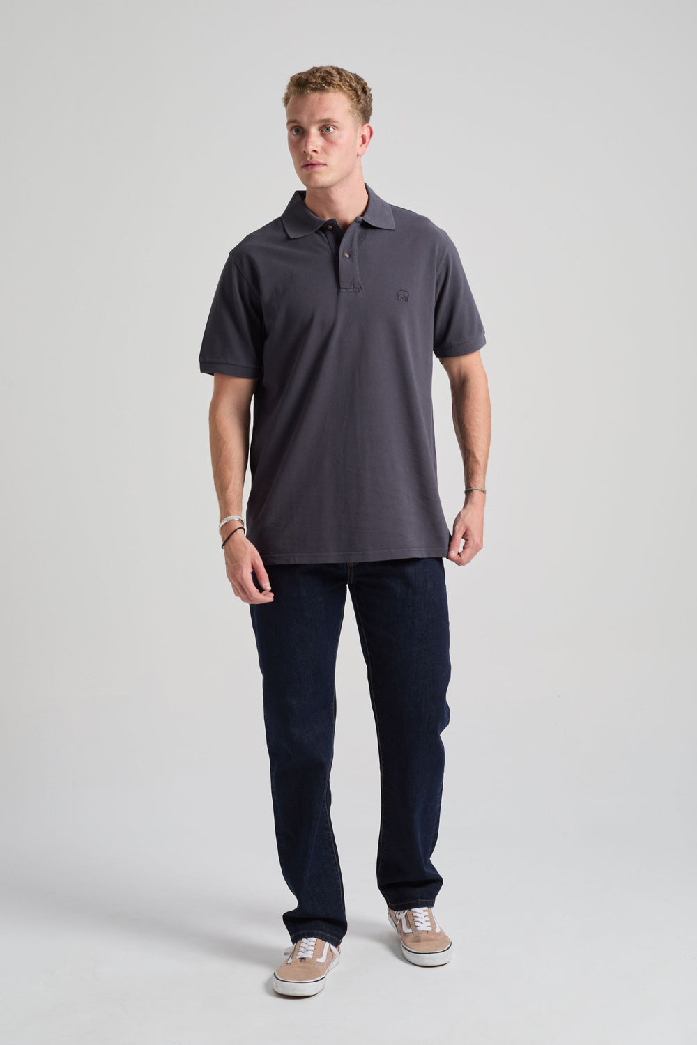 Personne portant l'Essential Polo en Bitumen Grey, associé à un jean et des baskets, face à l'appareil. | TP_IMAGE_TYPE=MODEL_FRONT