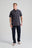 Personne portant l'Essential Polo en Bitumen Grey, associé à un jean et des baskets, face à l'appareil. | TP_IMAGE_TYPE=MODEL_FRONT