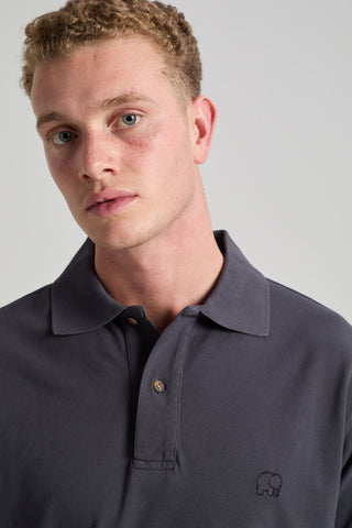 Personne portant un Essential Polo en Bitumen Grey, avec col classique et discret logo brodé. | TP_IMAGE_TYPE=MODEL_FRONT