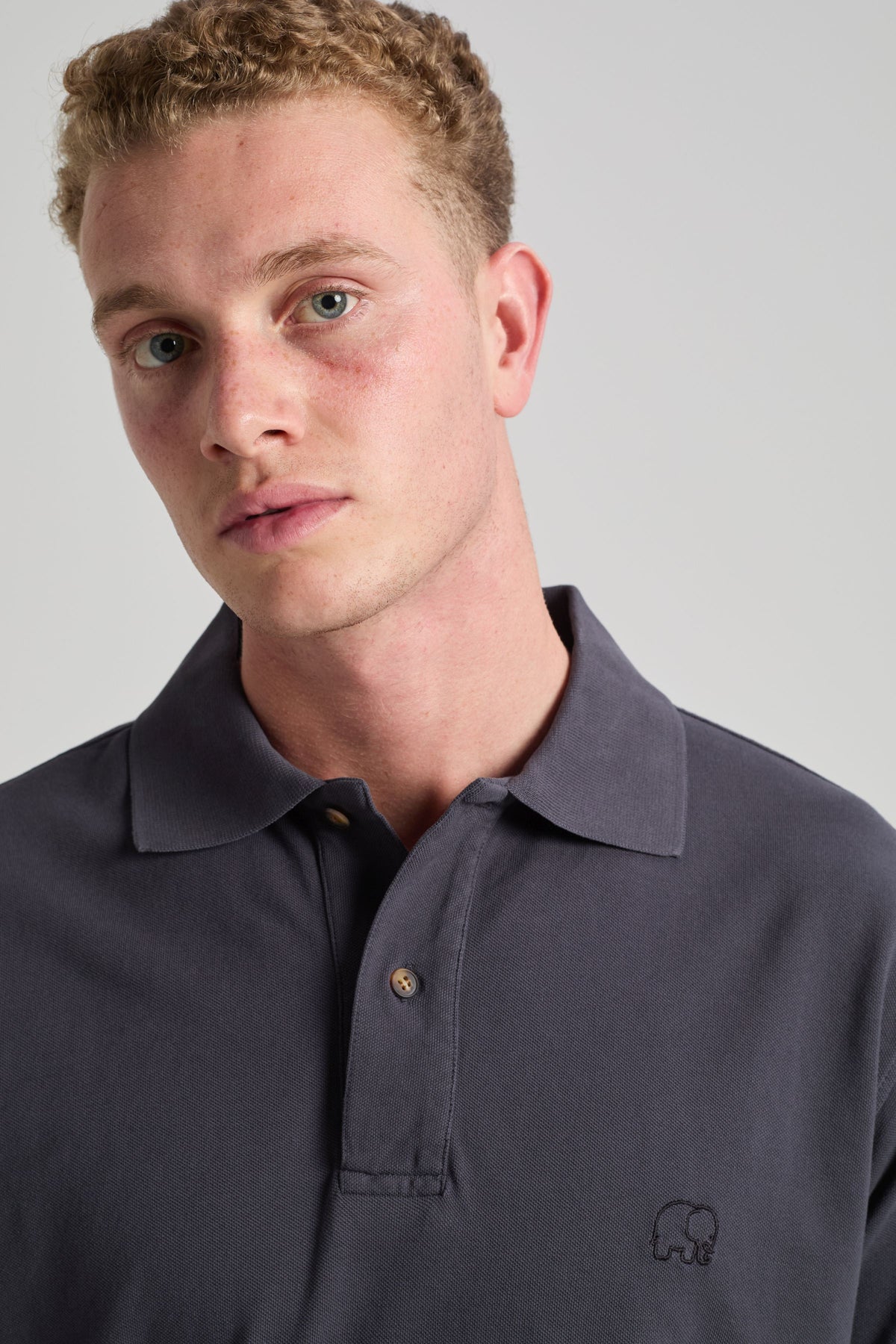 Personne portant un Essential Polo en Bitumen Grey, avec col classique et discret logo brodé. | TP_IMAGE_TYPE=MODEL_FRONT