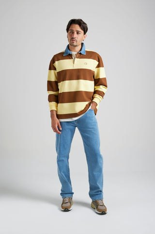 Personne portant un Yard Rugby Polo à rayures Cappuccino et Banana, associé à un jean en denim et des baskets, debout sur un fond clair. | TP_IMAGE_TYPE=MODEL_FRONT