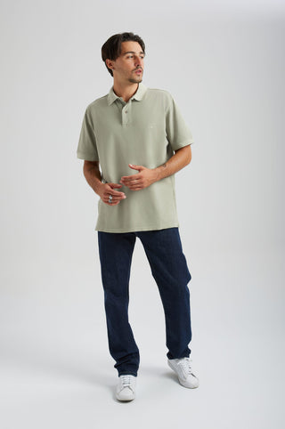 Person wearing an Essential Sunwashed Polo in Seagrass color, paired with dark denim pants, standing in a casual pose with a light background. | TP_IMAGE_TYPE=MODEL_FRONT