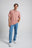 Persona che indossa la polo Essential Sunwashed Polo nel colore Old Rose con jeans azzurri e sneakers bianche, in piedi di fronte su uno sfondo neutro | TP_IMAGE_TYPE=MODEL_FRONT