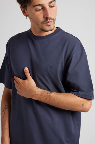 Personne portant un Essential T-Shirt en Parisian Blue, montrant la vue de face avec un gros plan du détail de la marque sur la poitrine | TP_IMAGE_TYPE=MODEL_FRONT