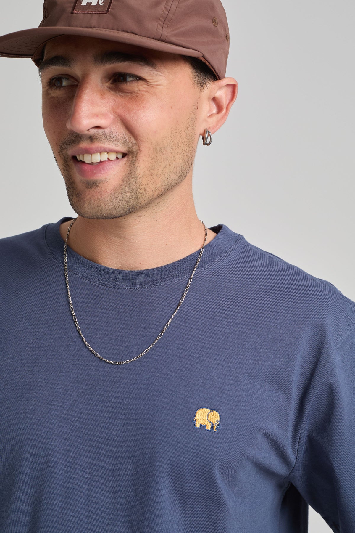Persona che indossa una Organic Essential T-Shirt in Trendsplant Blue con un piccolo logo elefante ricamato | TP_IMAGE_TYPE=MODEL_FRONT