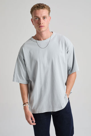Personne portant un t-shirt oversize épais en bleu perle, associé à un jean foncé et un collier. | TP_IMAGE_TYPE=MODEL_FRONT