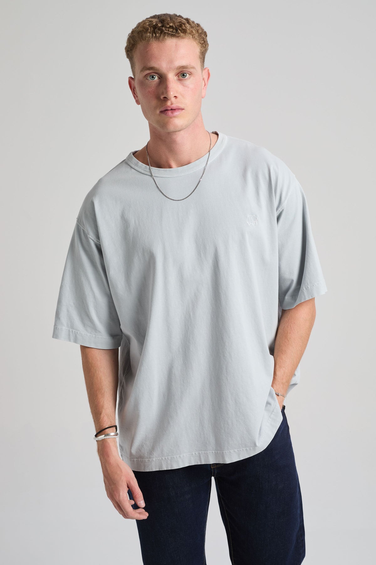 Personne portant un t-shirt oversize épais en bleu perle, associé à un jean foncé et un collier. | TP_IMAGE_TYPE=MODEL_FRONT