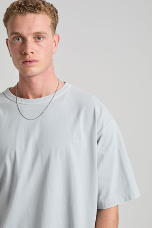 Personne portant le t-shirt oversize Essential Sunwashed Heavyweight en Pearl Blue, avec une coupe décontractée et un design simple. | TP_IMAGE_TYPE=MODEL_FRONT