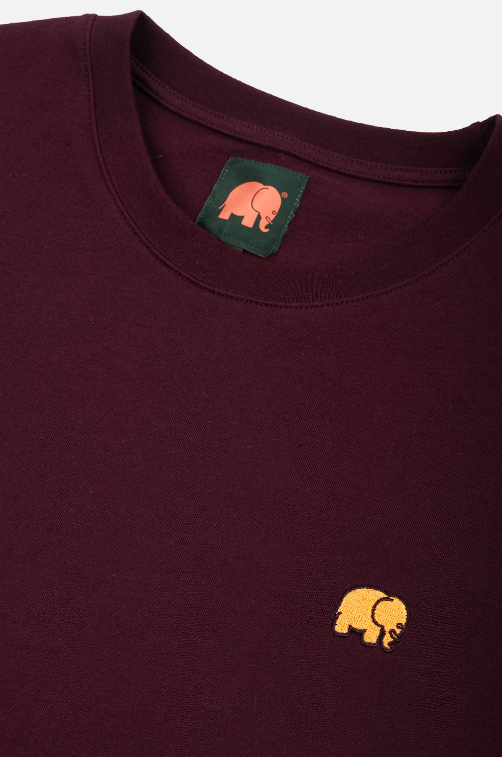 Dettaglio ravvicinato della t-shirt Essential biologica in rosso vino con logo elefante giallo | TP_IMAGE_TYPE=DETAIL