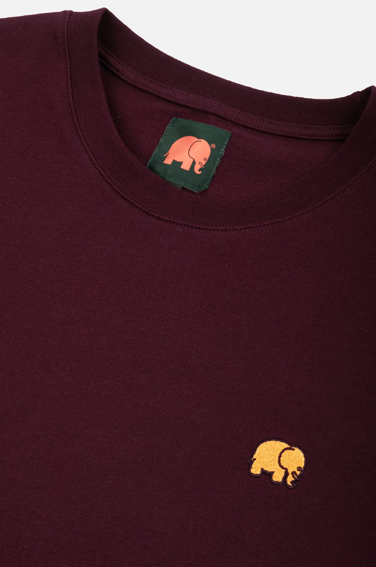 Dettaglio ravvicinato della t-shirt Essential biologica in rosso vino con logo elefante giallo | TP_IMAGE_TYPE=DETAIL