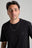 Personne portant un t-shirt Organic Essential noir avec un petit logo éléphant, accessoirisé d'un collier à chaîne en argent | TP_IMAGE_TYPE=MODEL_FRONT