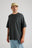 Personne portant un t-shirt oversize épais en Pirate Black, associé à un jean bleu clair et une casquette beige, debout devant un fond neutre. | TP_IMAGE_TYPE=MODEL_FRONT