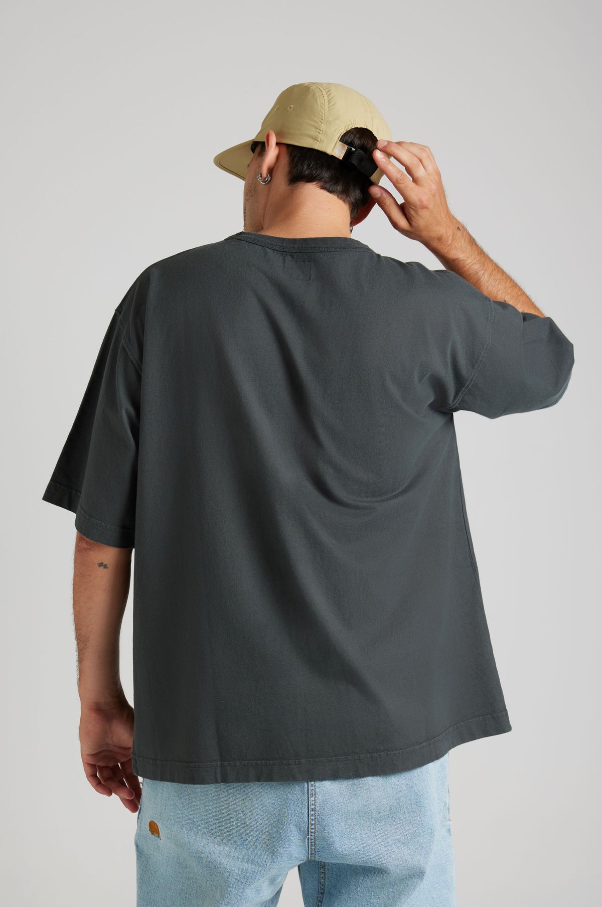 Personne portant un t-shirt oversize en tissu épais, coloris Pirate Black, vue de dos, ajustant une casquette. | TP_IMAGE_TYPE=MODEL_BACK