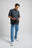 Person wearing an Essential T-Shirt in Bitumen Grey, holding a hat while standing in a casual pose. | TP_IMAGE_TYPE=MODEL_FRONT