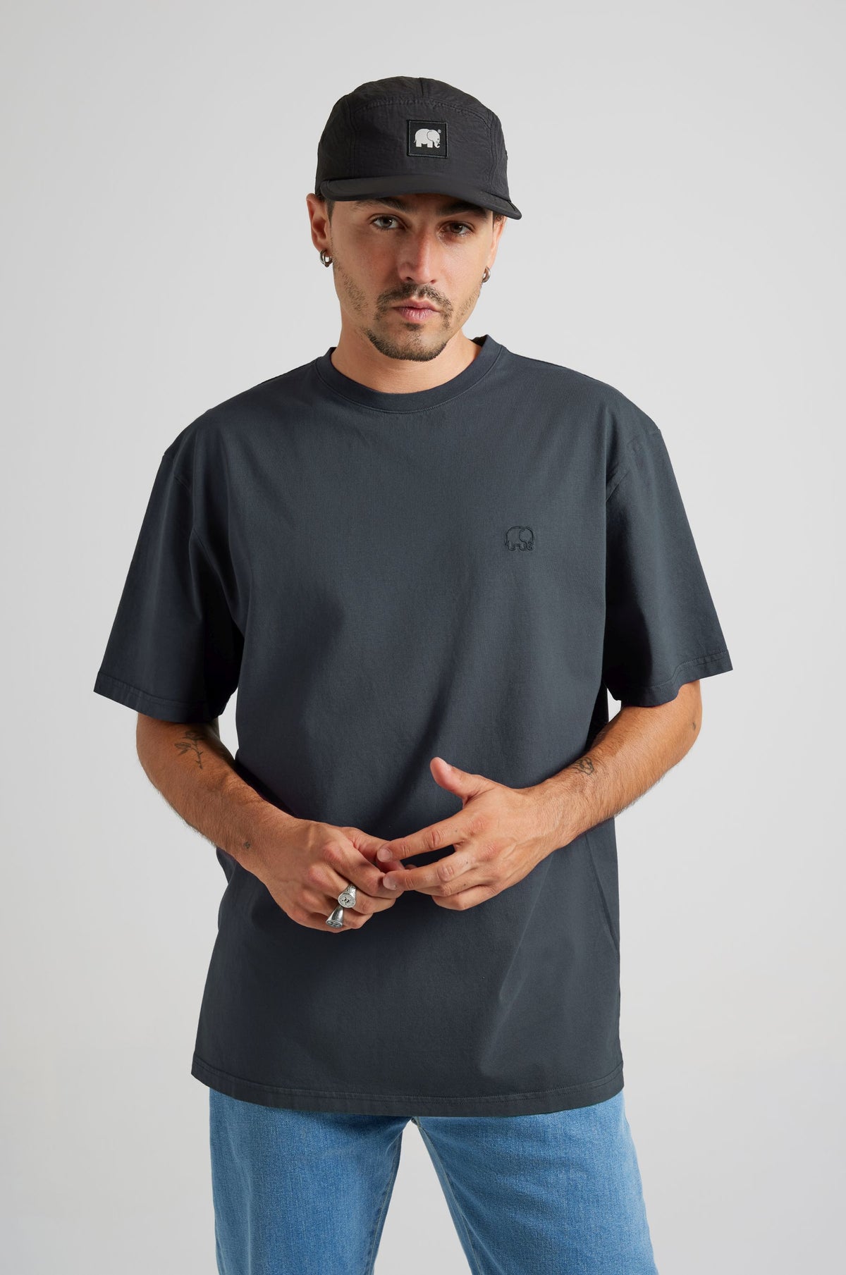 Person wearing an Essential T-Shirt in Bitumen Grey, styled with blue jeans, posing against a neutral background. | TP_IMAGE_TYPE=MODEL_FRONT