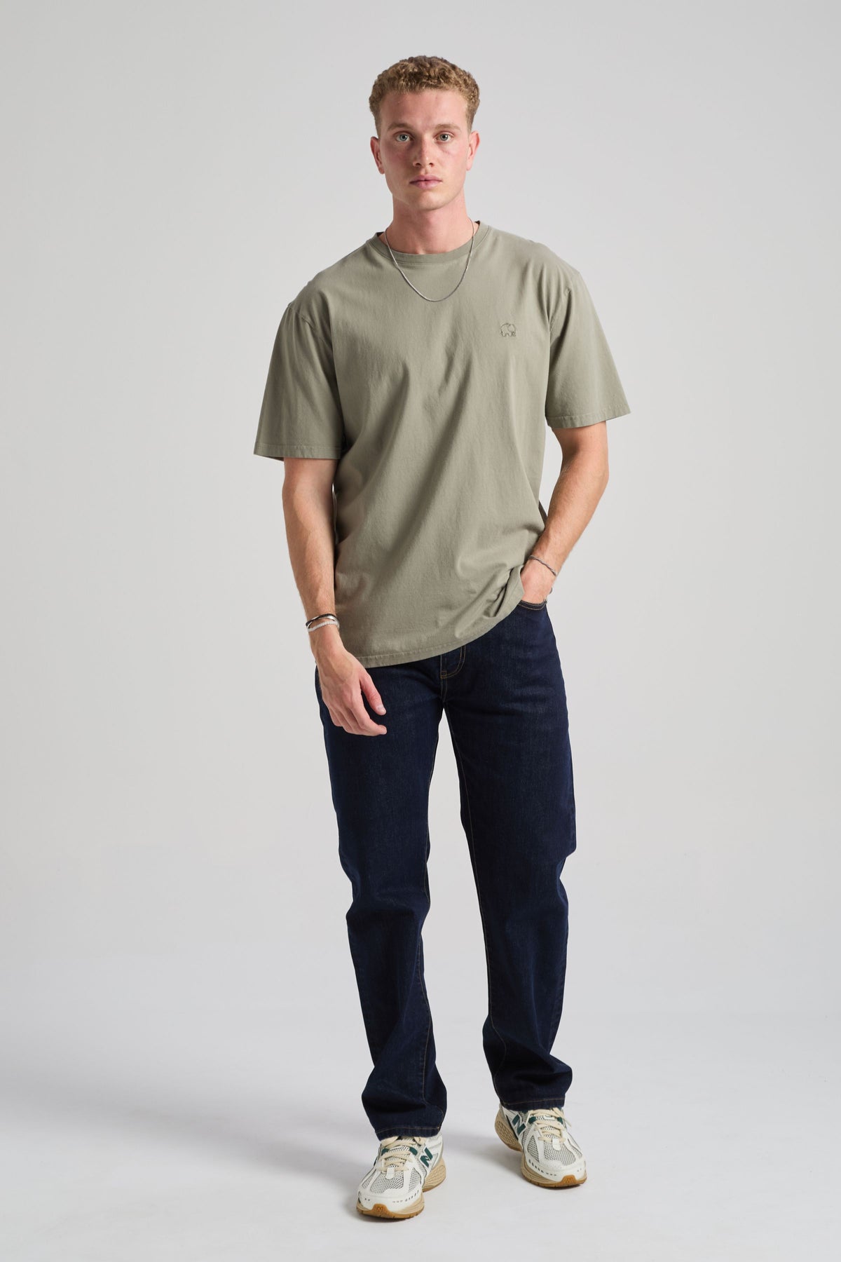 Person wearing an agave green essential t-shirt, styled with dark jeans and sneakers, standing in a neutral background | TP_IMAGE_TYPE=MODEL_FRONT