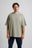 Persona che indossa una t-shirt oversize pesante sunwashed Essentials in seagrass, in posa su uno sfondo neutro. | TP_IMAGE_TYPE=MODEL_FRONT