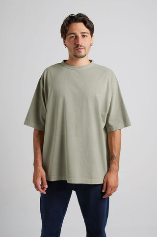 Persona che indossa una t-shirt oversize pesante sunwashed Essentials in seagrass, in posa su uno sfondo neutro. | TP_IMAGE_TYPE=MODEL_FRONT