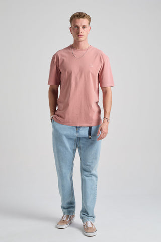 Personne portant un Essential Sunwashed T-Shirt en Old Rose, associé à un jean bleu clair et des baskets, debout devant un fond uni | TP_IMAGE_TYPE=MODEL_FRONT