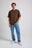 Person wearing an Essential T-Shirt in Carafe Brown paired with light blue jeans and white sneakers, standing in a relaxed pose. | TP_IMAGE_TYPE=MODEL_FRONT