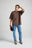 Personne portant un t-shirt oversize dans un riche coloris chocolat, associé à un jean bleu clair et tenant une casquette bordeaux. | TP_IMAGE_TYPE=MODEL_FRONT