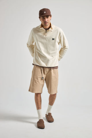 Persona che indossa Ecodye Cotton Climber Shorts Sand, abbinati a un top chiaro e a un berretto marrone, in posa naturale davanti a uno sfondo neutro | TP_IMAGE_TYPE=MODEL_FRONT