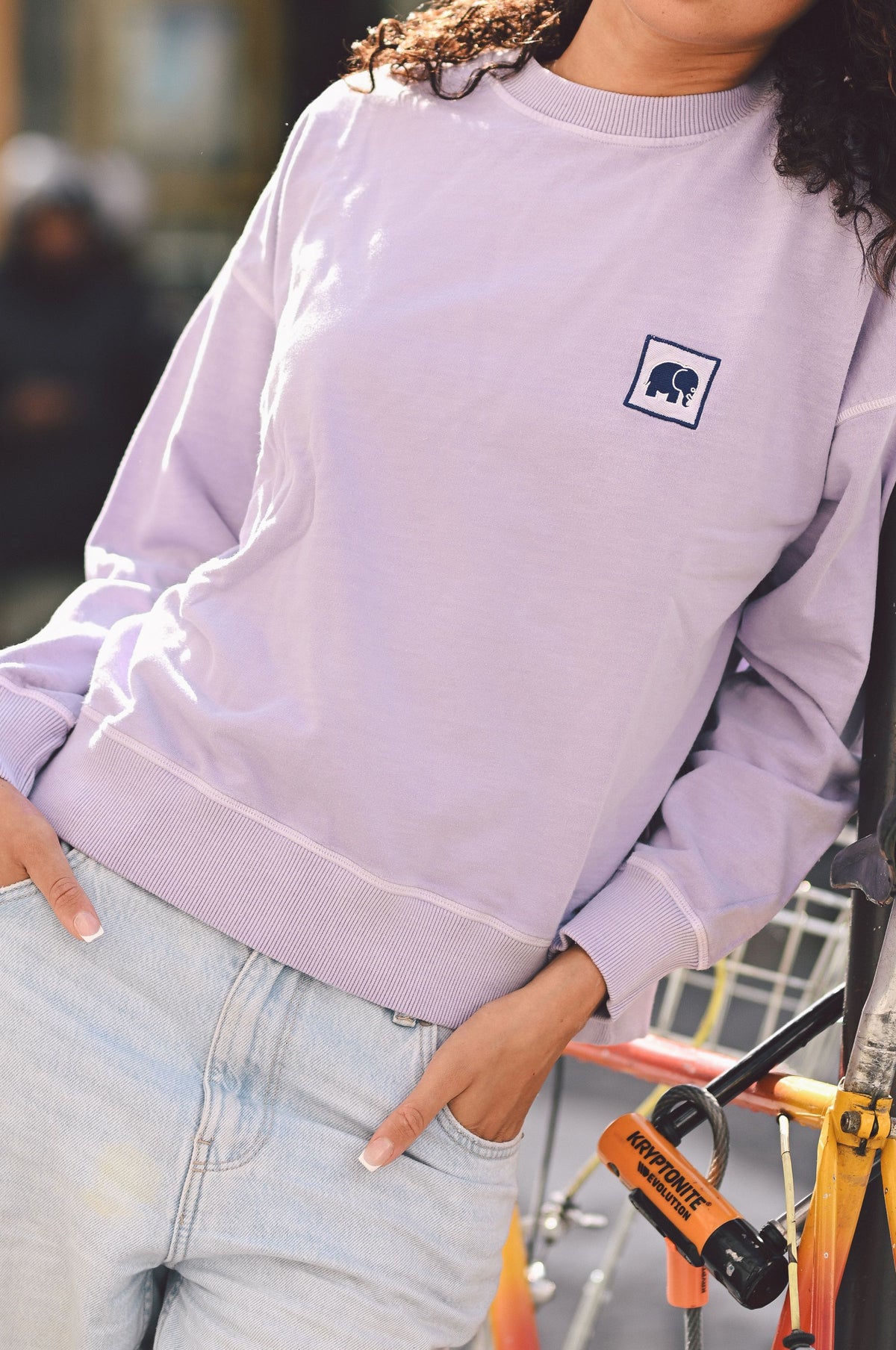Personne portant un sweat-shirt oversize lavande avec un logo, vue de face | TP_IMAGE_TYPE=MODEL_FRONT