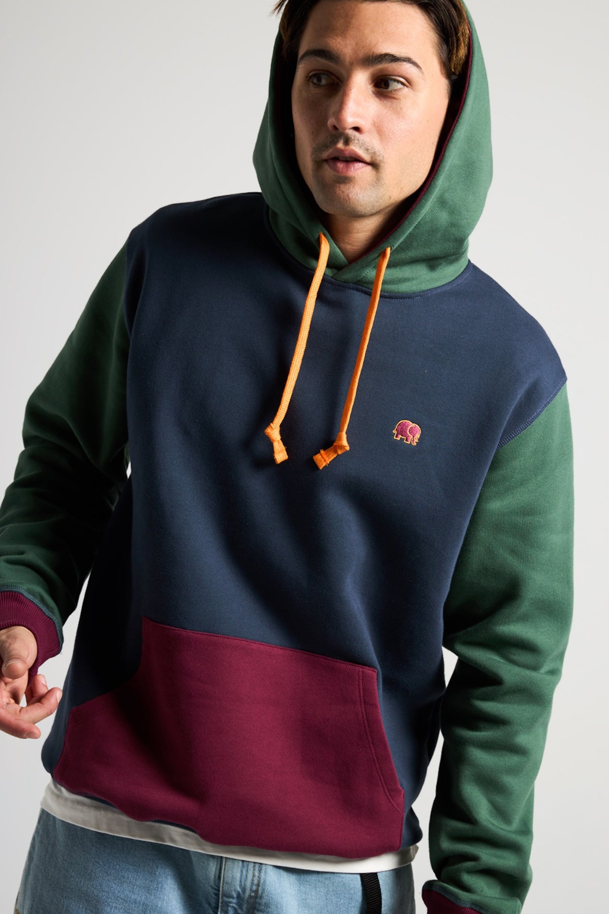 Personne portant un sweat à capuche color block biologique bleu, vert et bordeaux avec cordons orange | TP_IMAGE_TYPE=MODEL_FRONT